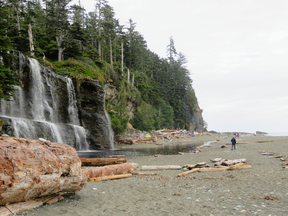 A camping site on a beach along the West Coast Trail next to a waterfall.