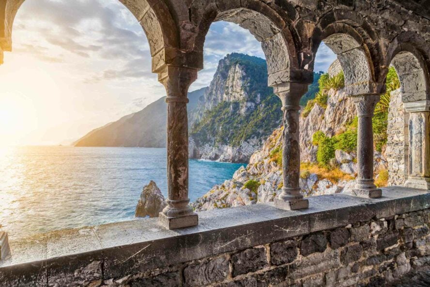 Ancient columns of the gothic Church of St. Peter with a mountain view and shoreline scenery at sunset. In the town of Porto Venere, in La Spezia, Italy.