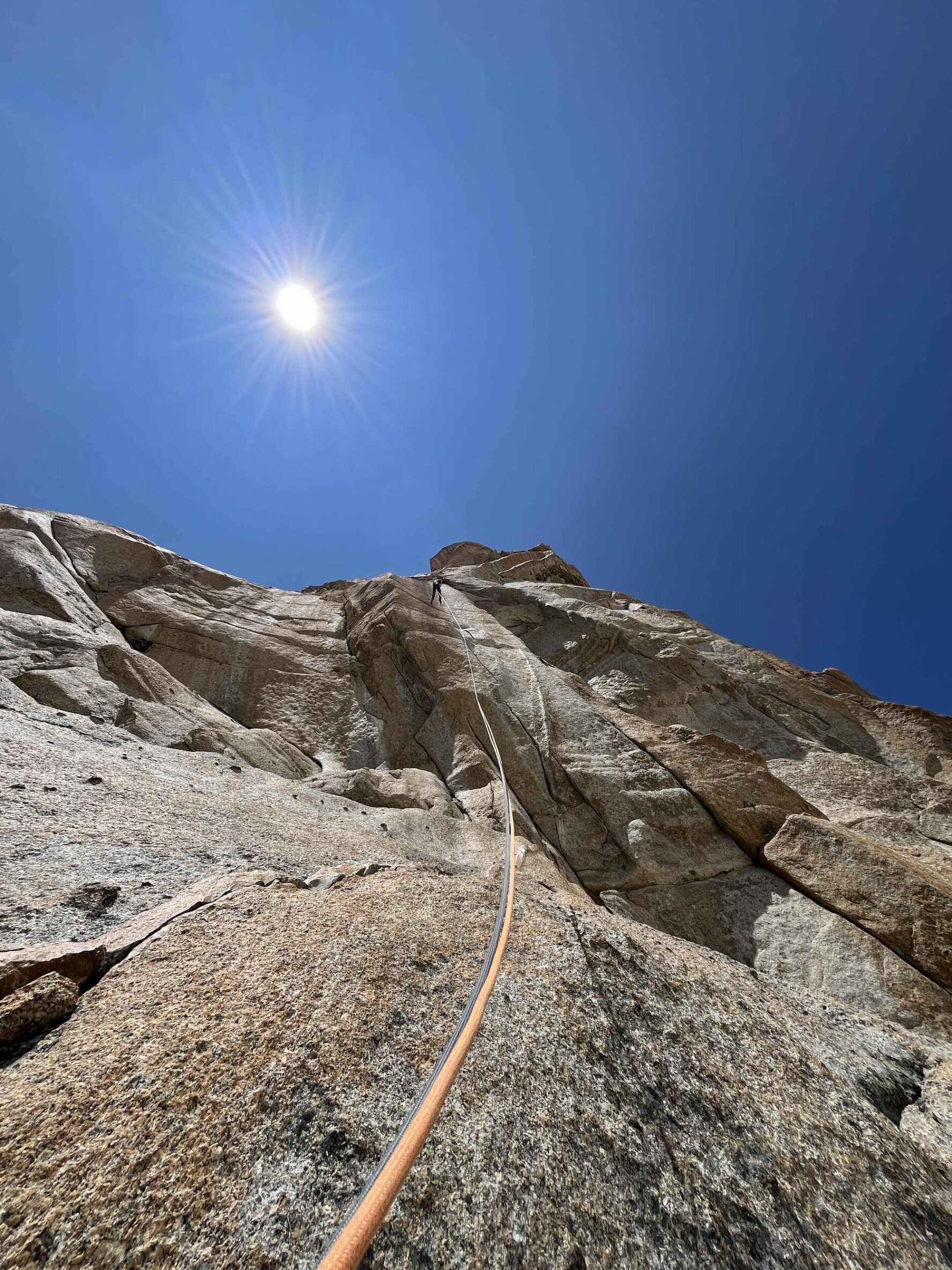 View of a climber ascending a rock from below on a sunny day