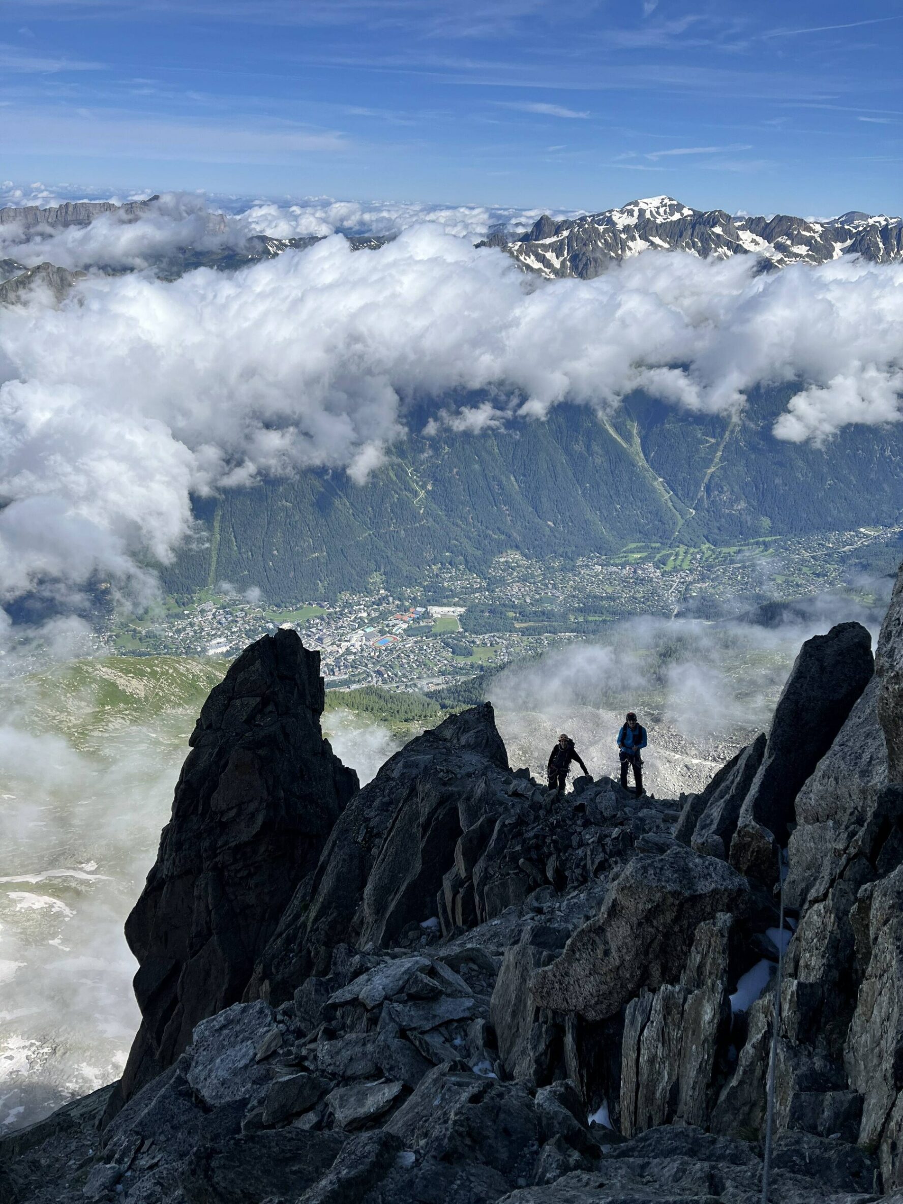 Two climbers on a rocky ridge with the Chamonix valley and peaks in the background
