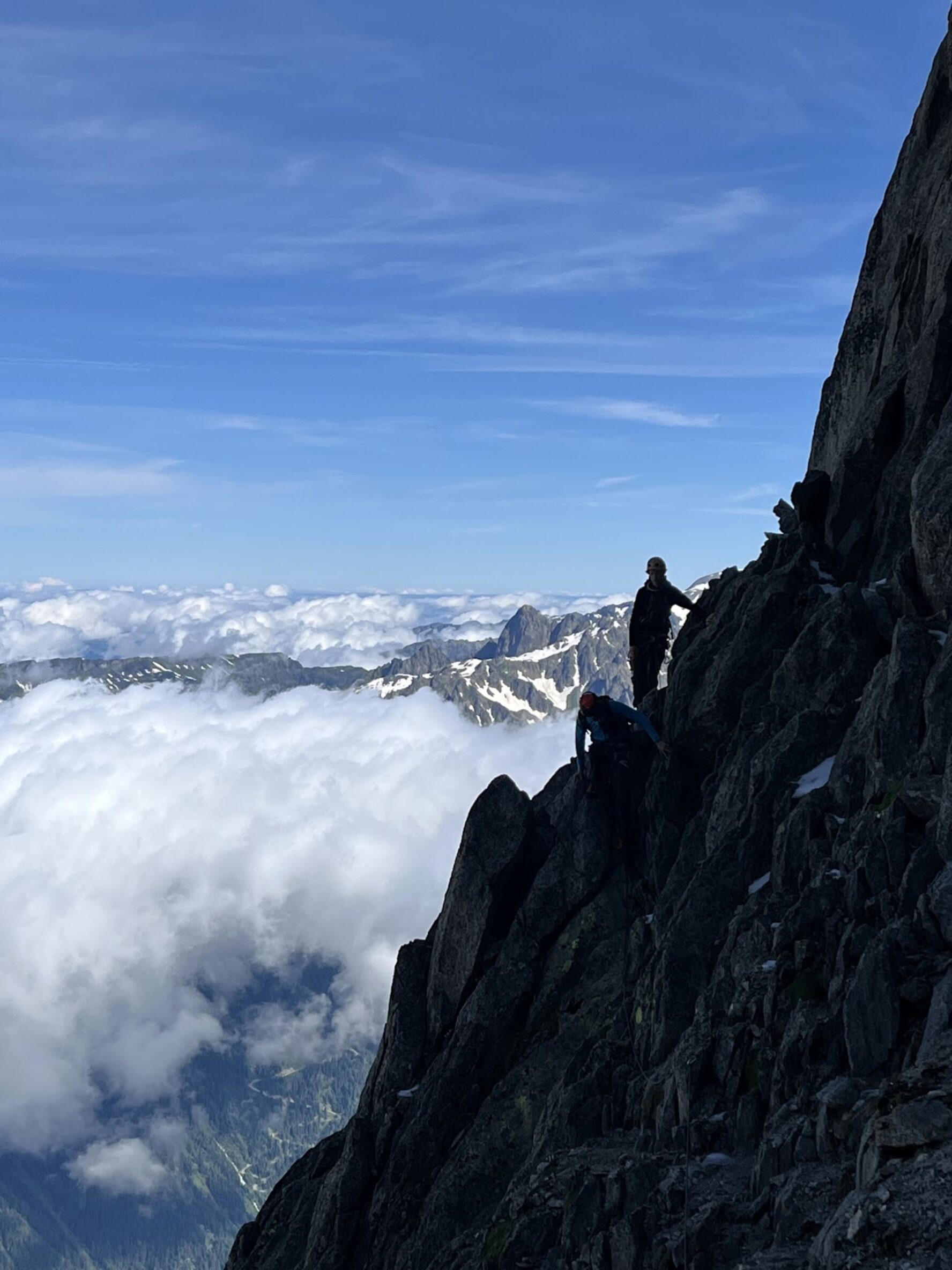 Two climbers scaling a rock face with Alpine peaks in the background