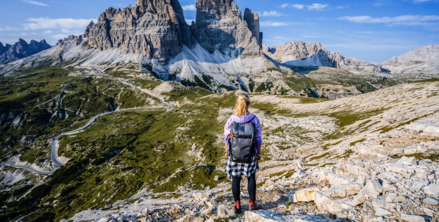 Lone female hiker watching Tre Cime di Lavaredo from afar.