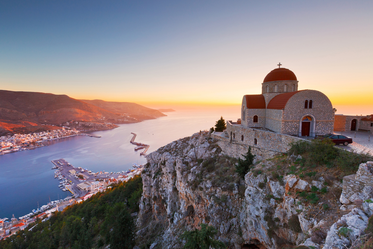 A view of a church and a coastal village in Kalymnos, Greece, at sunset.