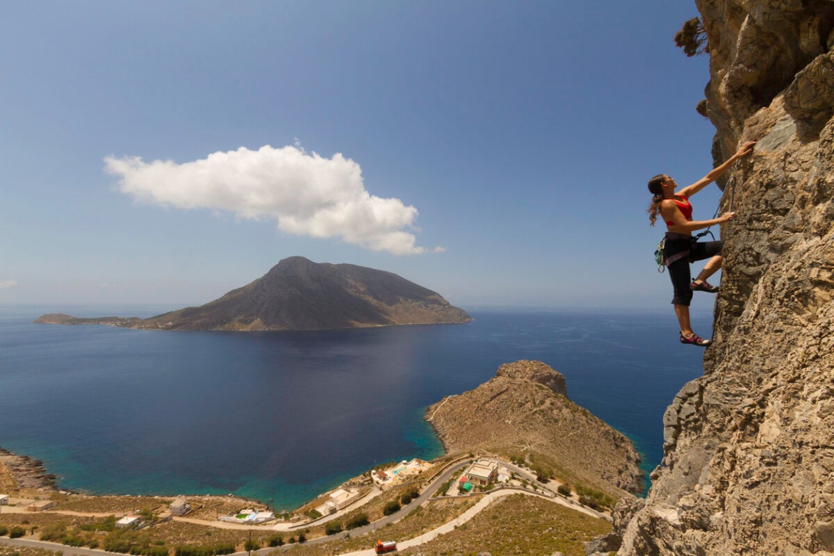 A woman rock climbing near a beautiful vista in Kalymnos