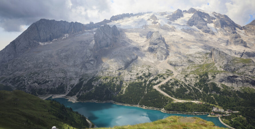 Woman taking a photograph of Lake Fedaia and the Marmolada mountain