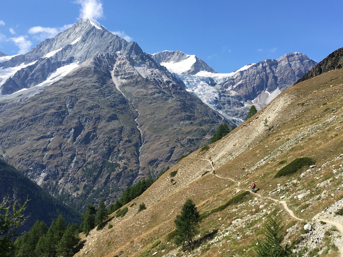 A high-elevation MTB trail cutting across a steep slope in the Swiss Alps near Verbier.