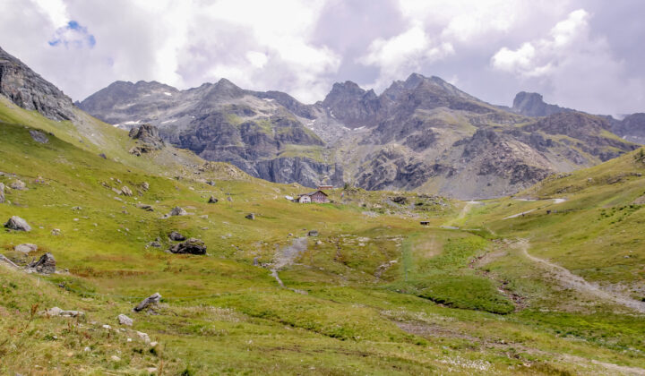 Remote high-mountain rifugio Gabiet in the Italian Alps, surrounded by peaks and grasslands.