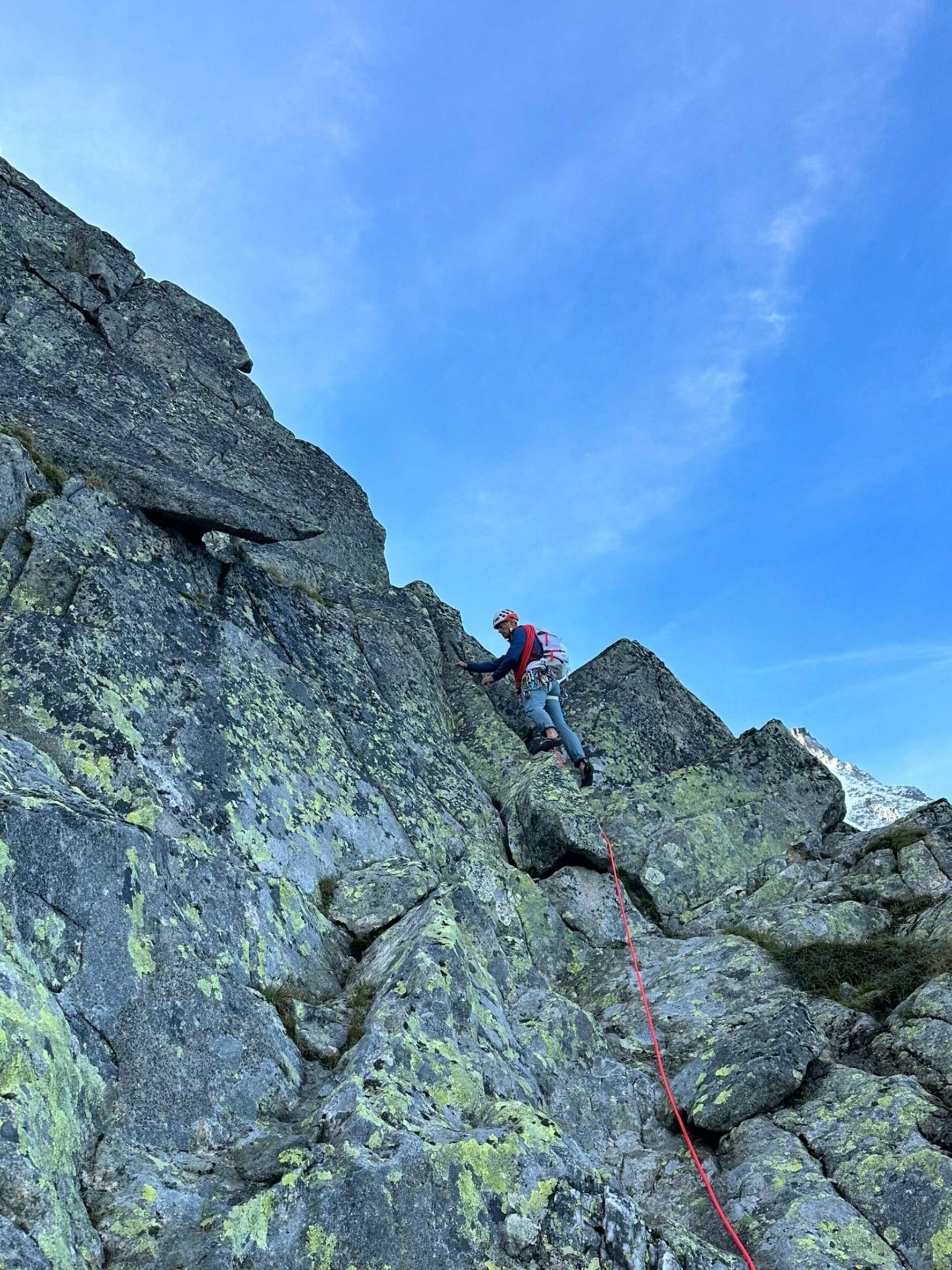 A climber ascends a steep alpine rock face in the Chamonix area