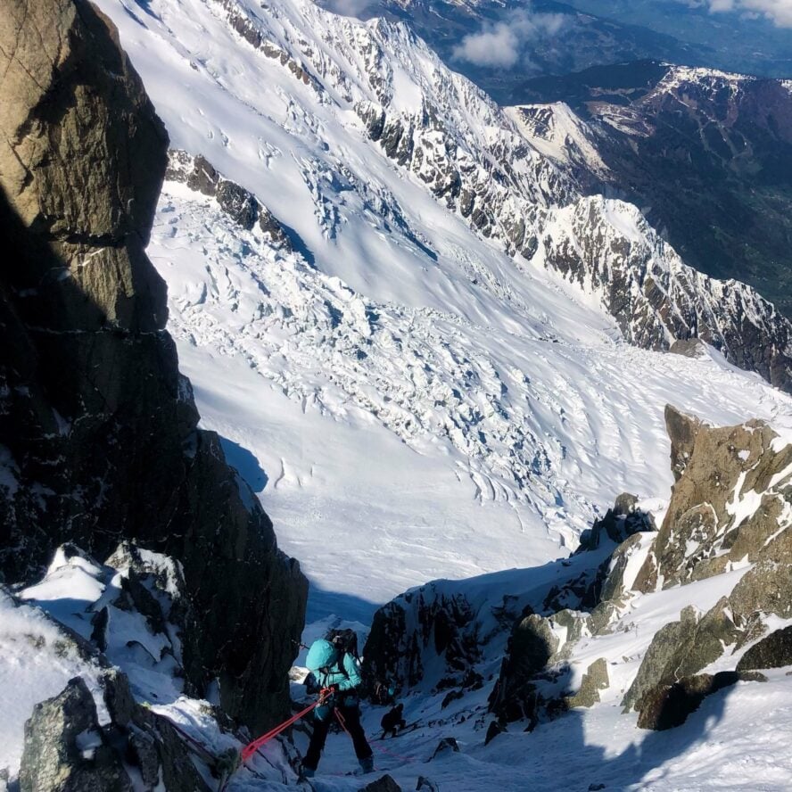 Ski mountaineer rappelling into a couloir in the French Alps.