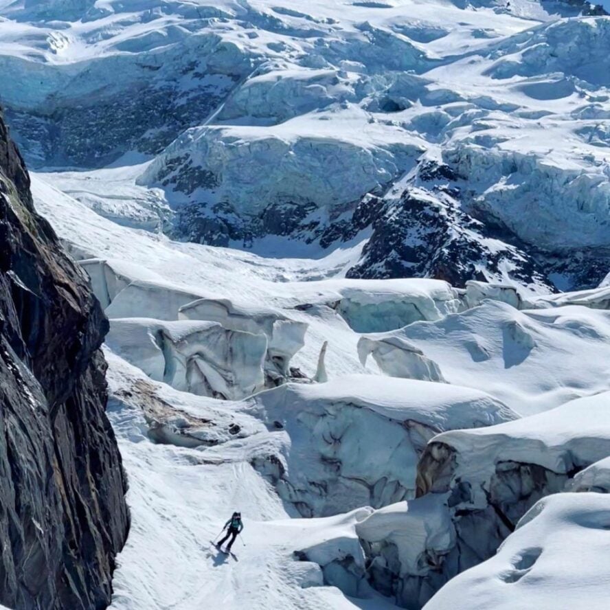 Ski tourer navigating glaciated terrain full of crevasses and ice bridges.