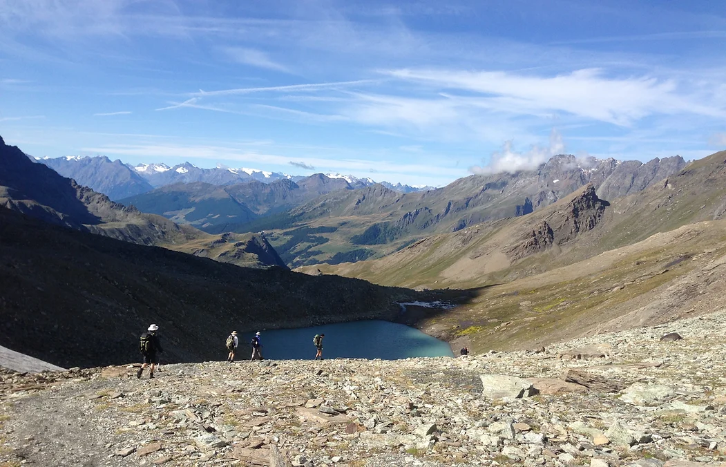 Hikers following a trail along an alpine lake in Switzerland.