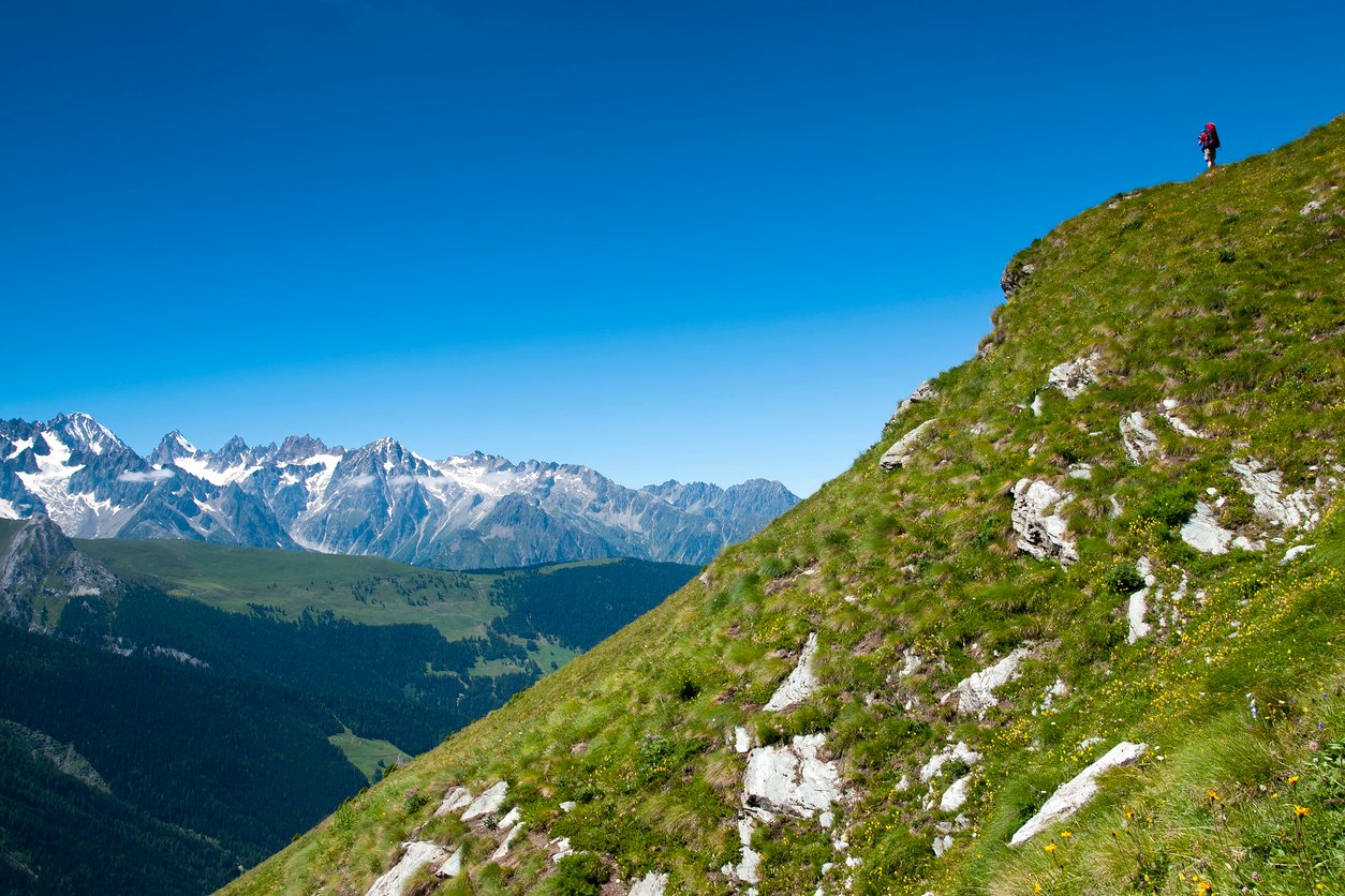 A hiker on a hillside along the Tour des Combins trek.