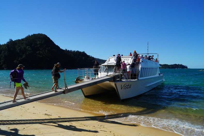 People boarding a boat on a beach in Abel Tasman National Park. 