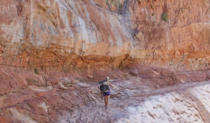 A hiker on a cliffside trail in the Grand Canyon