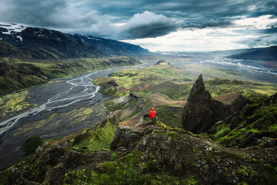 Hiker standing on top of Valahnukur, view of Thórsmörk valley and Krossa river.