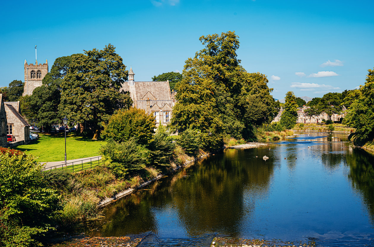 Churches hidden behind some trees by the river Kent in Kendal.