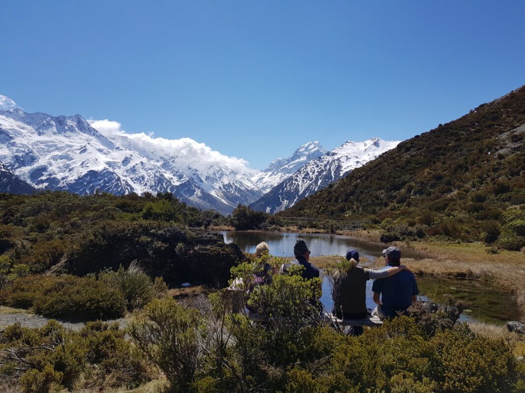 Hikers sitting in front of a mountainous vista in New Zealand