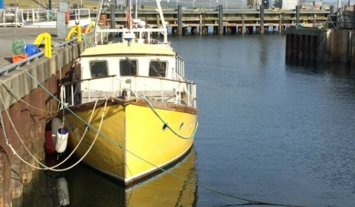 A boat anchored in the harbor in a seaside town in the Orkney Islands.