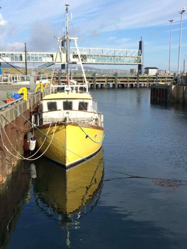 A boat anchored in the harbor in a seaside town in the Orkney Islands.