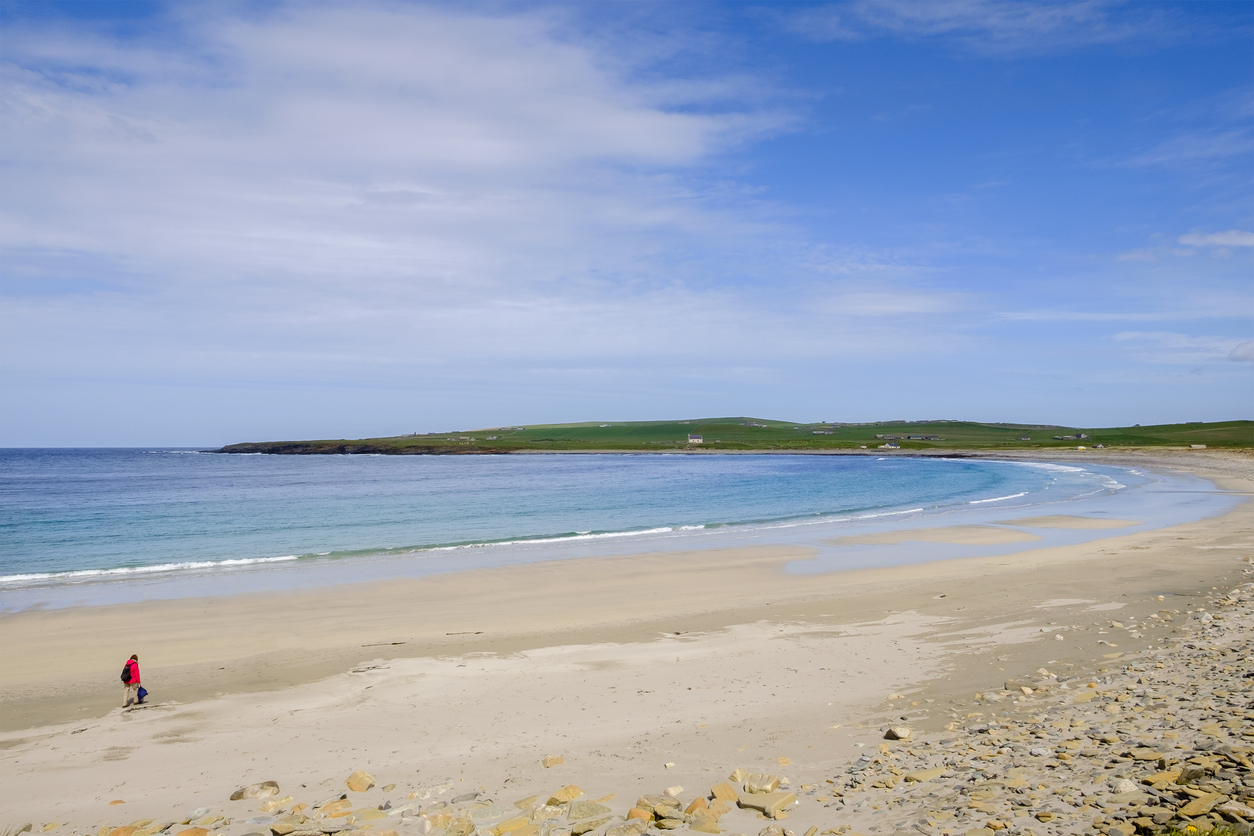 Hiker near the historic Skara Brae settlement in the Orkneys, Scotland.