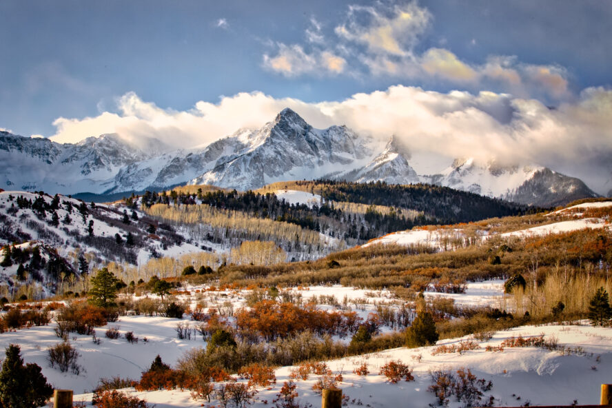  A landscape shot of the wintry San Juan Mountains with clouds billowing over the peaks.