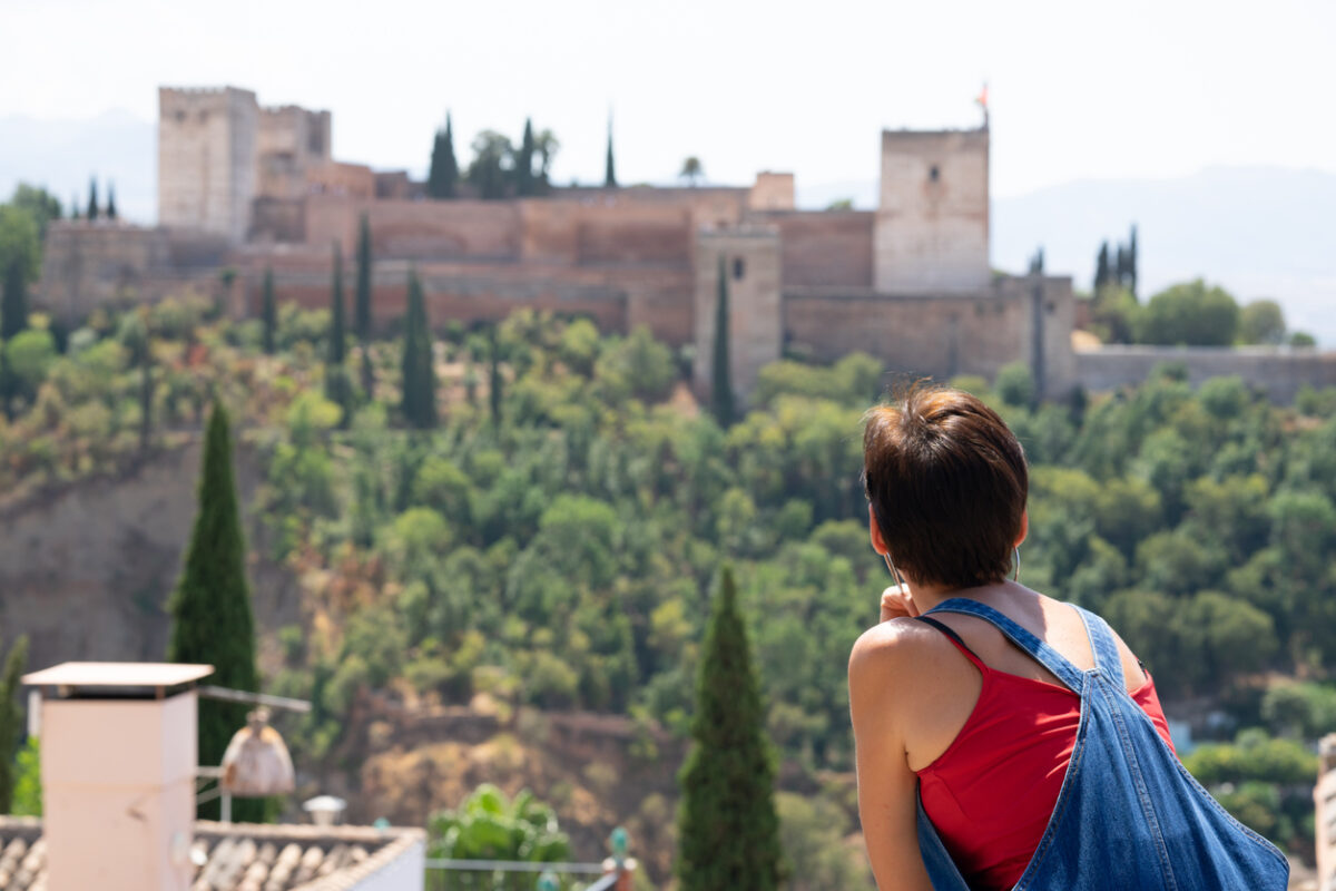 A tourist in Granada enjoying views of the palace-fortress of Alhambra. 