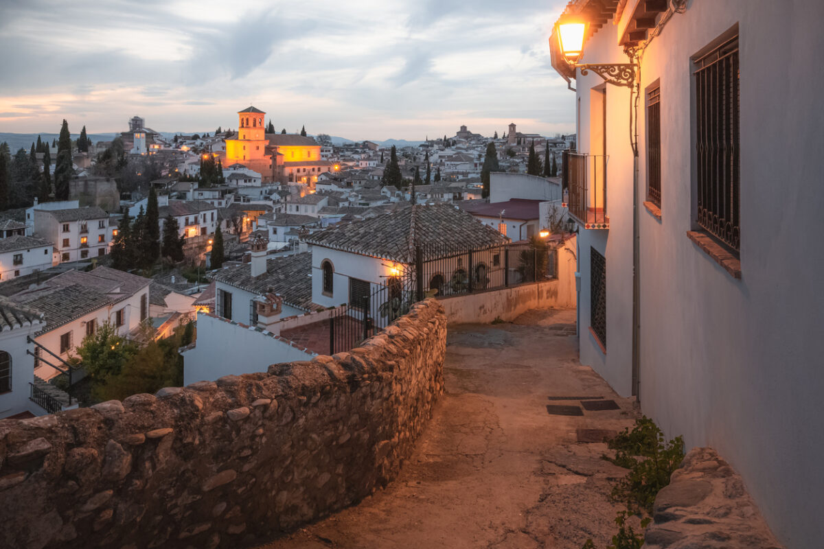 An alley in Granada looking over typical white houses and a church.