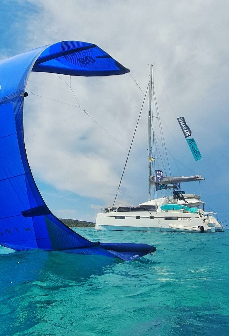 Kitesurfer in Sardinia with sailing catamaran in the background