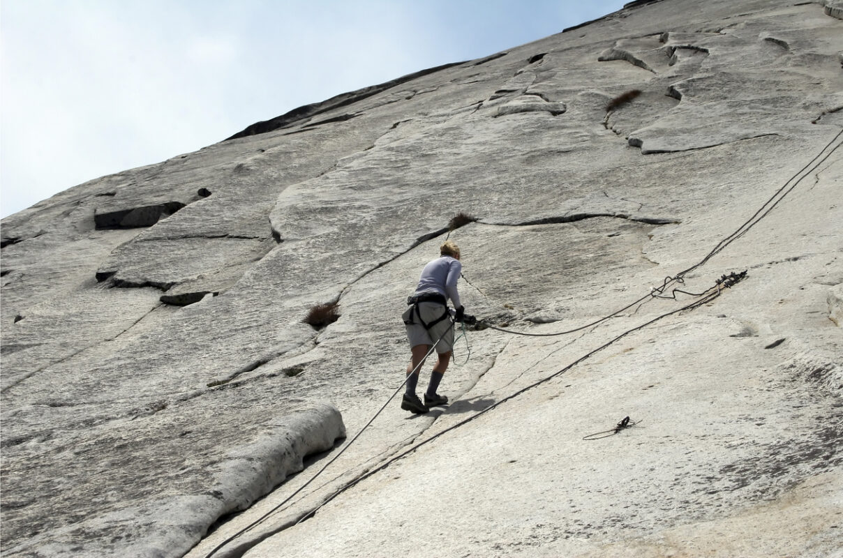 A hiker climbing up the Half Dome in Yosemite using a rope. 