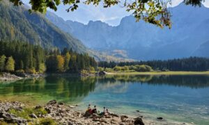 Group of people sitting by Lake Fusine in Italy