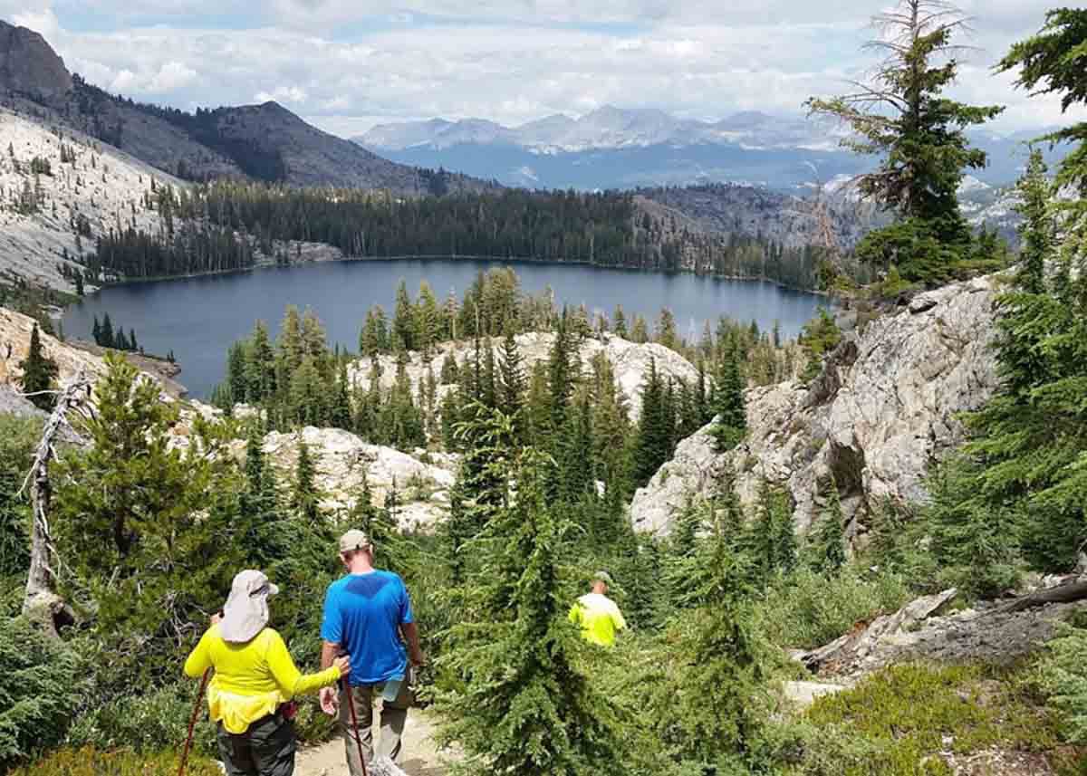 Hikers walking in a forest toward a lake, in Yosemite.