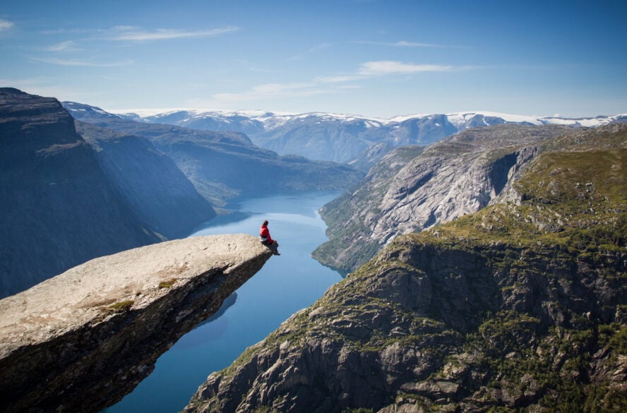 Hiker sitting at the edge of the Trolltunga rock in Norway