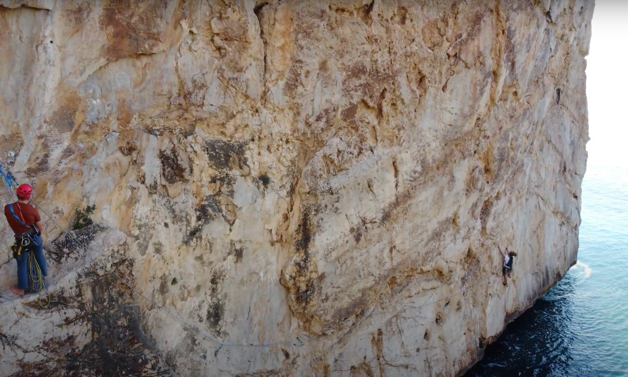 Two climbers climbing a wall directly by the sea on the Costa Blanca, Spain.