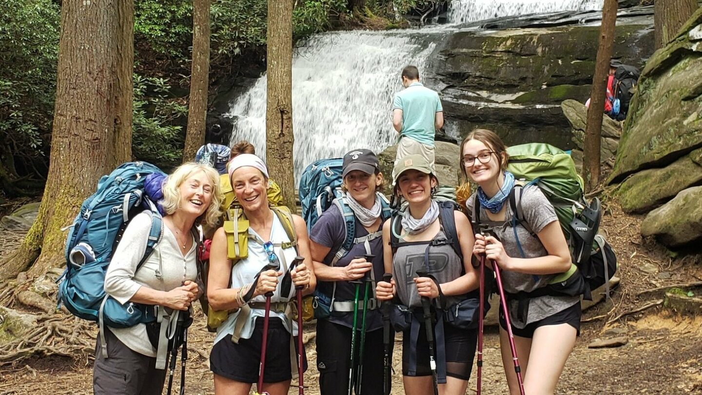 Group of female hikers enjoying the ambiance of a waterfall.