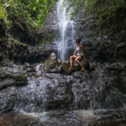 Female hiker resting at a waterfall on the Ka’au Crater Trail