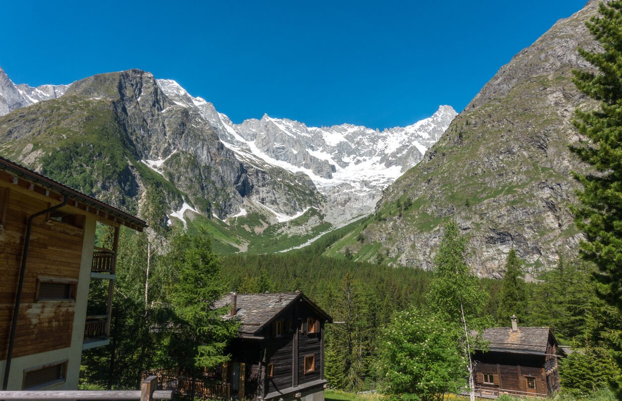 A Swiss village of La Fouly with traditional wooden houses and glaciated peaks in the distance.