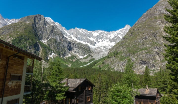 A Swiss village of La Fouly with traditional wooden houses and glaciated peaks in the distance.
