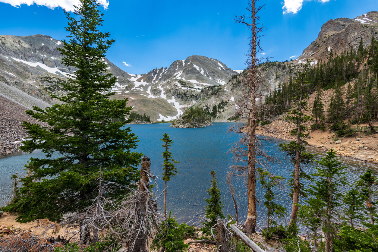 A high-altitude sapphire alpine lake in Colorado’s Rocky mountains, situated in the Cameron Pass areas, surrounded by mighty peaks and pines.