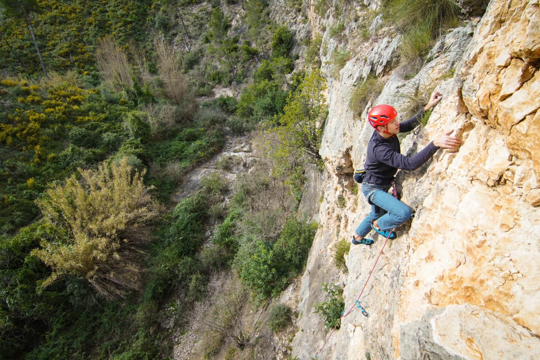 A climber climbing a limestone cliff in the Alicante mountains near the Spanish coast.