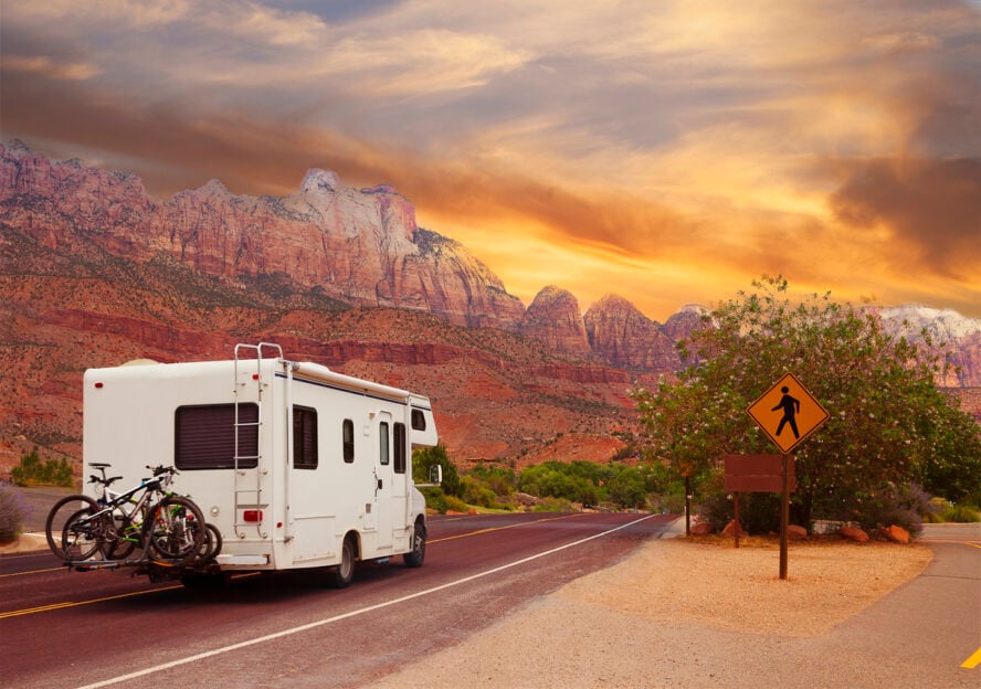 RV in front of high desert red rocks.