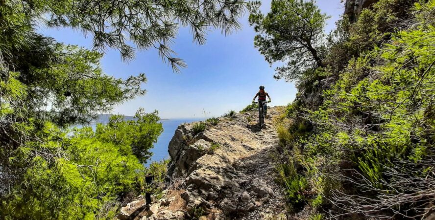 An MTB rider riding a steep downhill in the shade on Vis, Croatia.