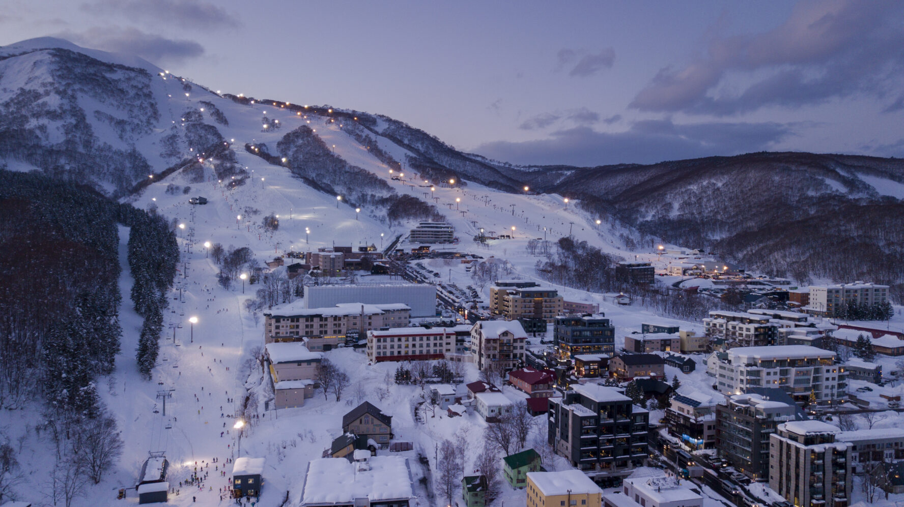 A zoomed out view of Niseko village at night with lights.