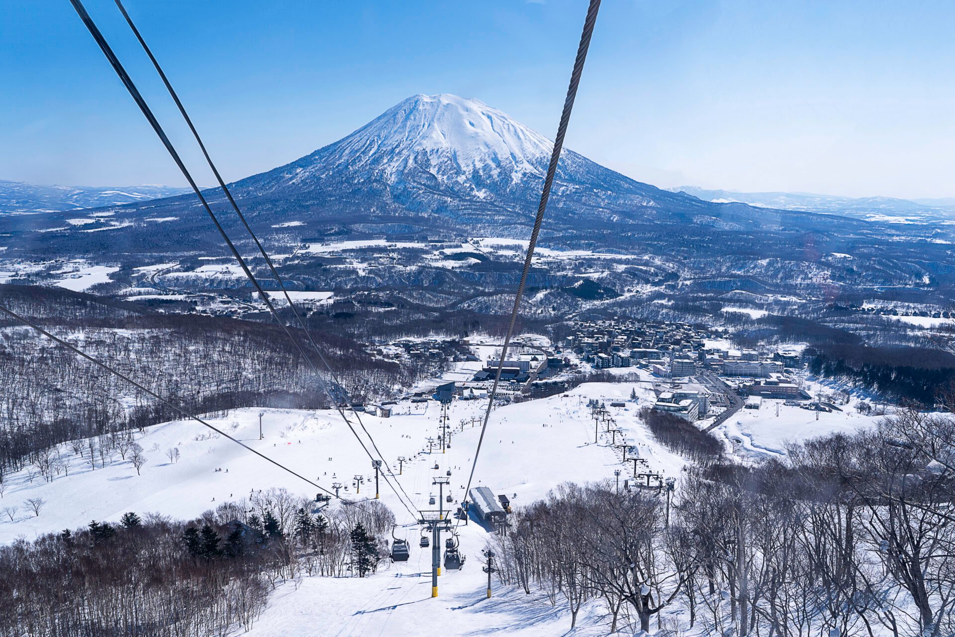A ski resort with a gondola and a volcano shape mountain in the background.