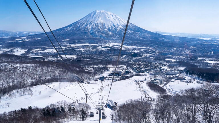 A ski resort with a gondola and a volcano shape mountain in the background.