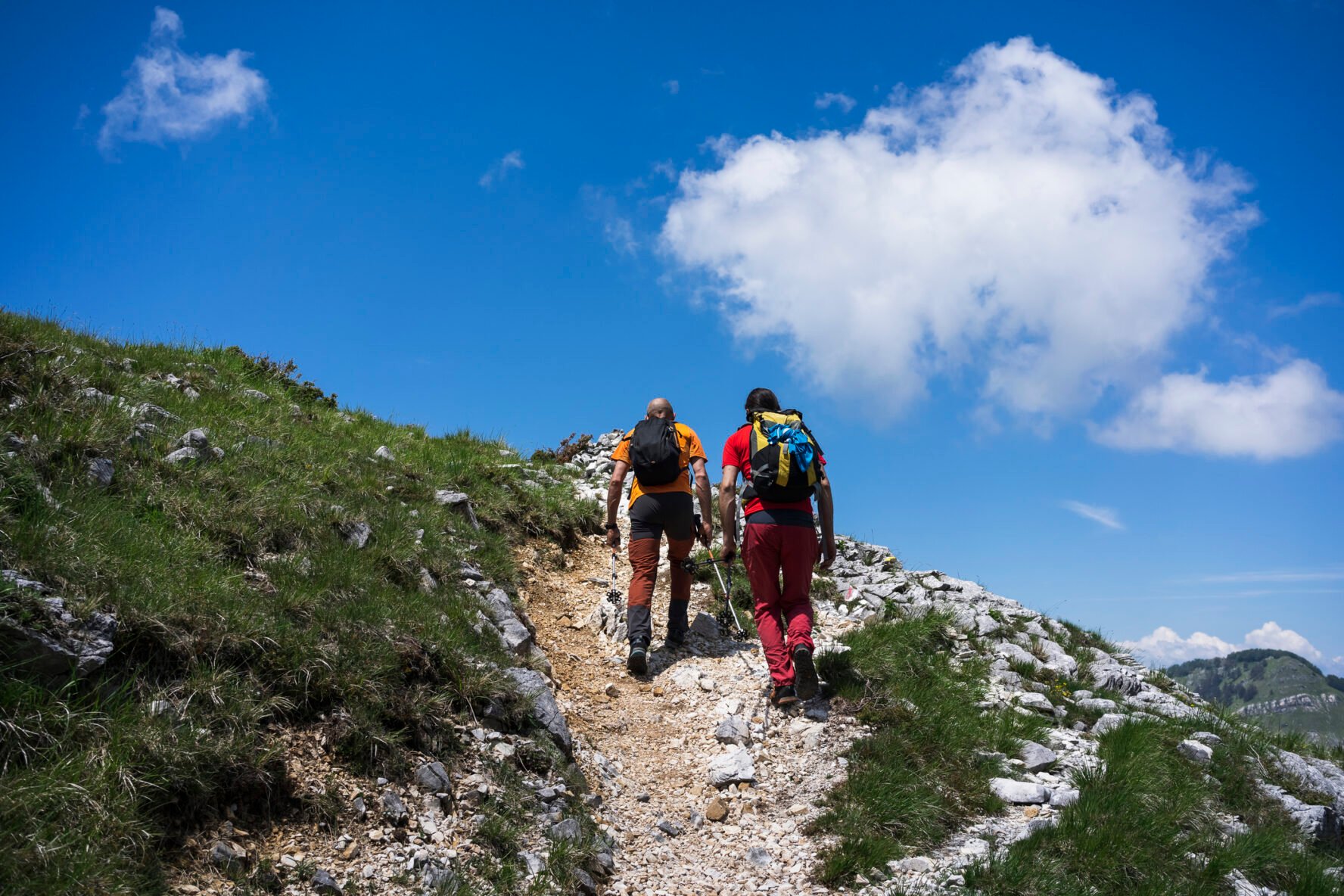 Two hikers on their way to reach a summit in the mountains of Tuscany.