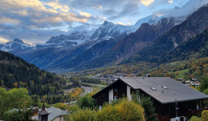 Chamonix valley with typical Alpine architecture and green areas surrounded by mighty snow-capped peaks.