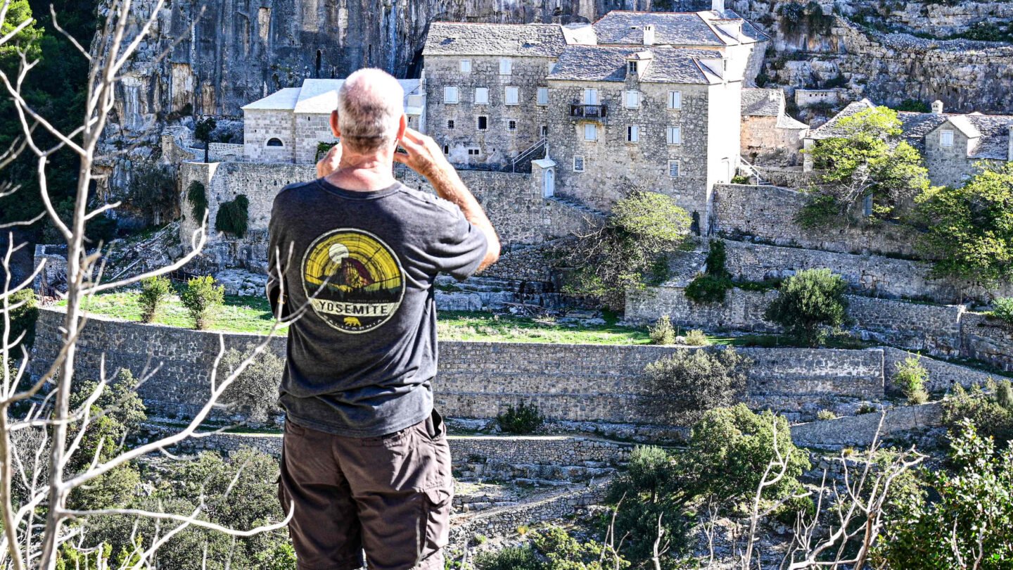 Hiker photographing the Blaca monastery on the island of Brač