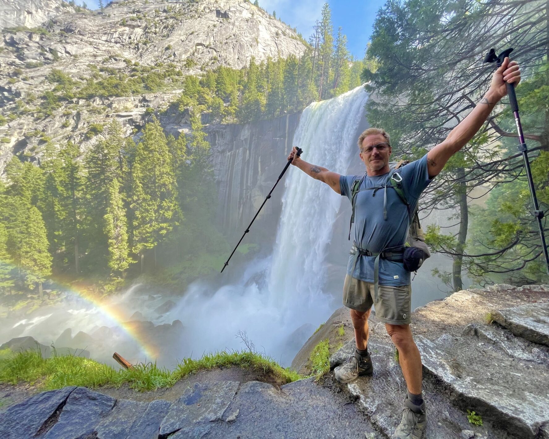 A hiker posing with hiking poles on the Mist Trail