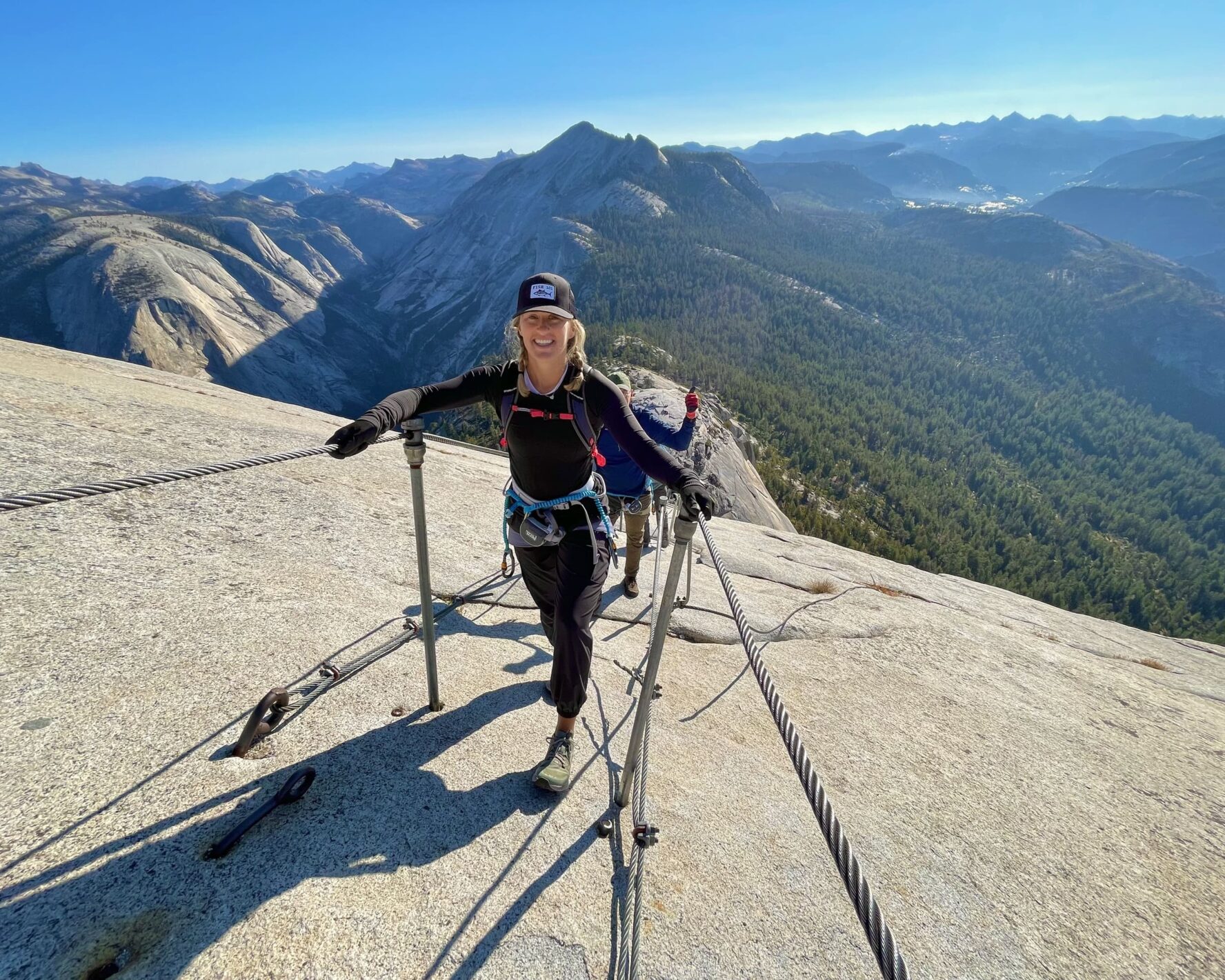 A woman hiker smiling while climbing the Half Dome cables