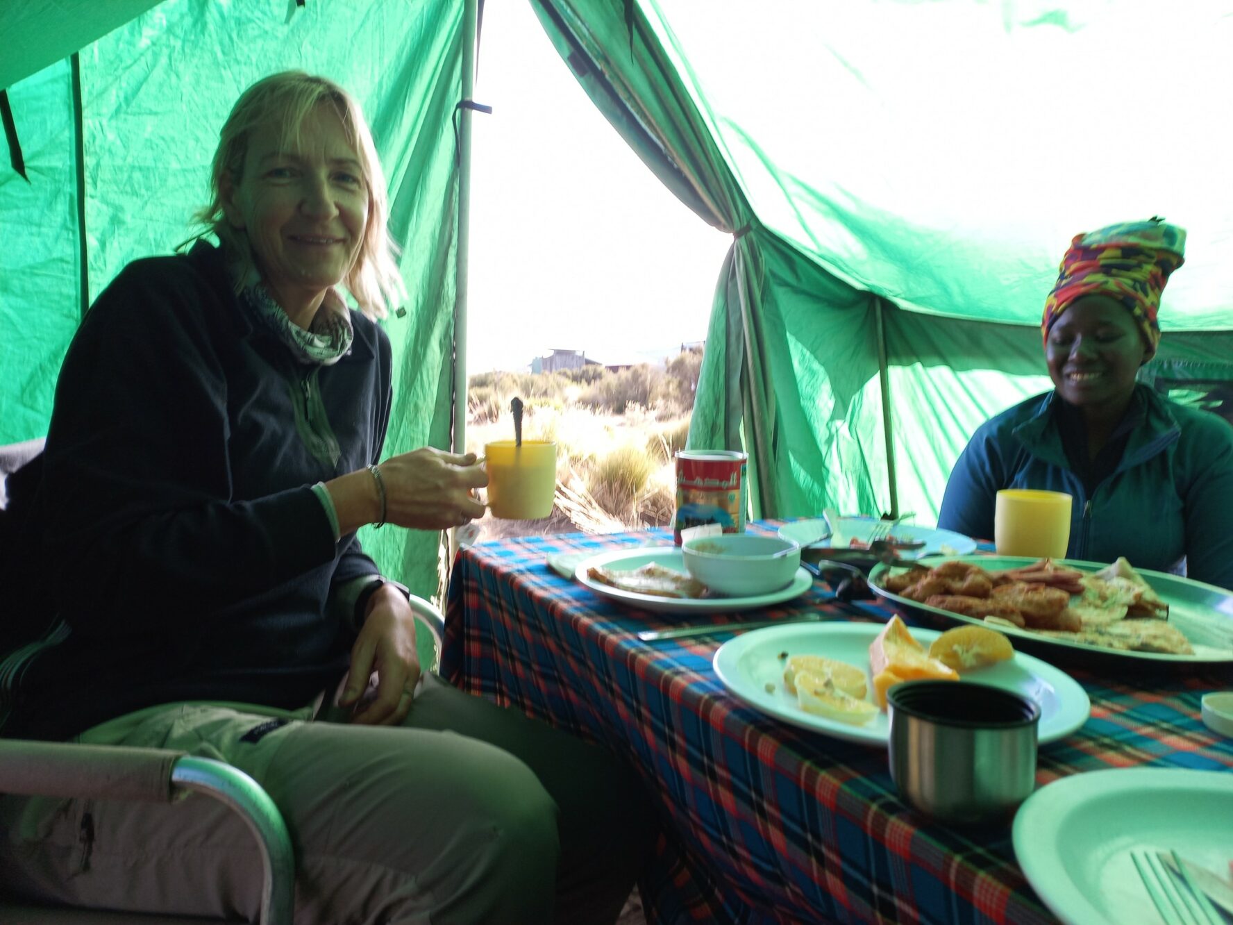 Trekker and her guide enjoying breakfast at a camp on their way to the top of Kilimanjaro.